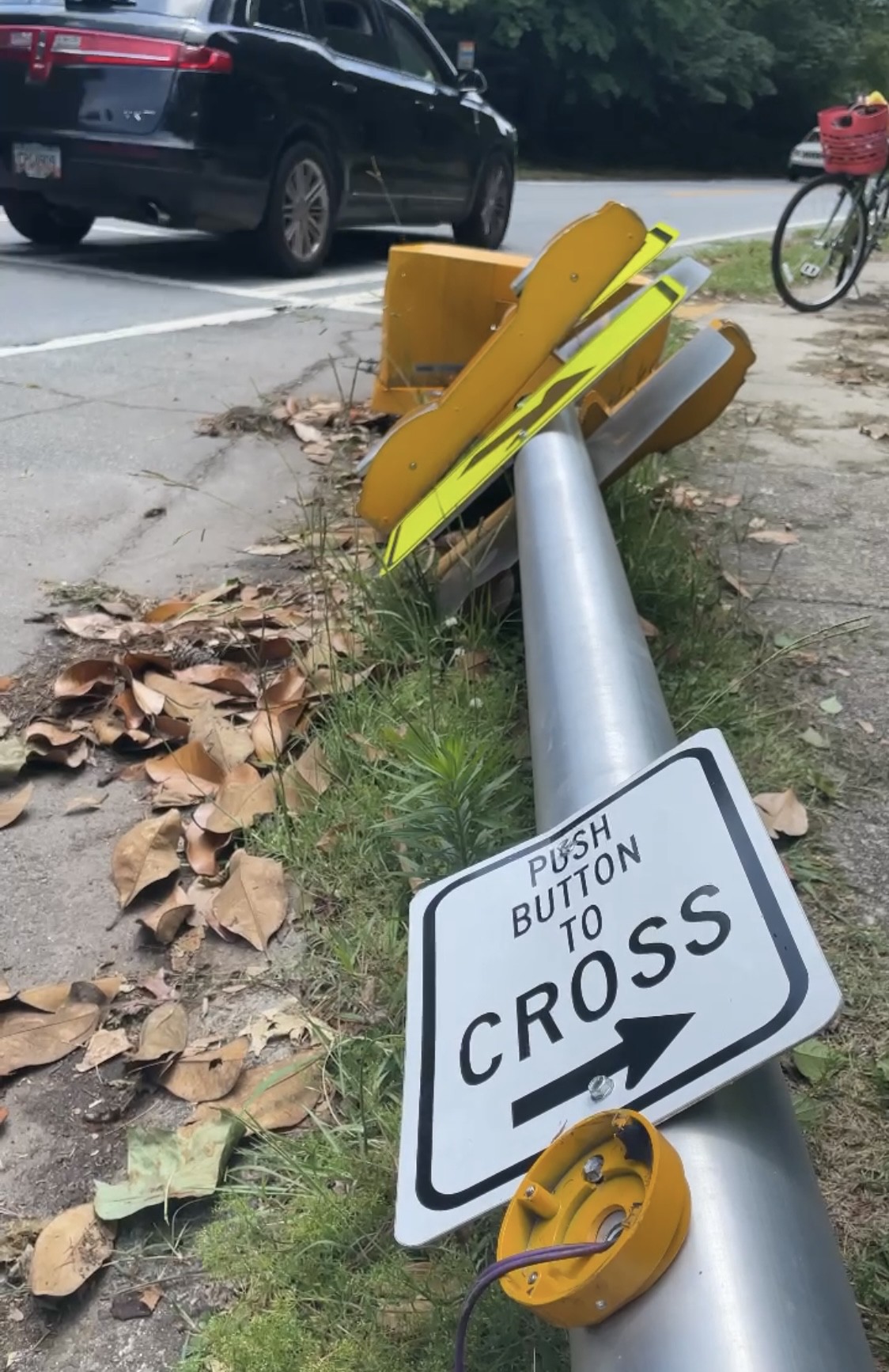 Crosswalk push-button pole laying on the ground in a school zone